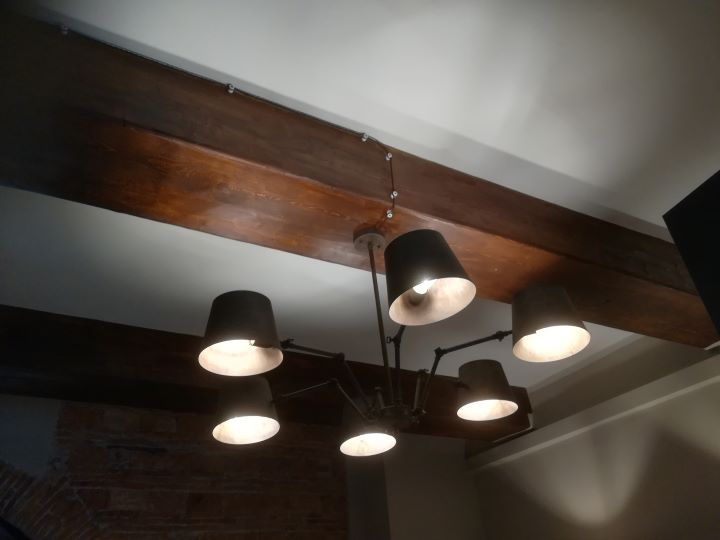 Lampadario a sei bracci installato su trave in legno con cavo a treccia a vista, realizzato da Electrica Ligure per impianto elettrico civile di un'enoteca